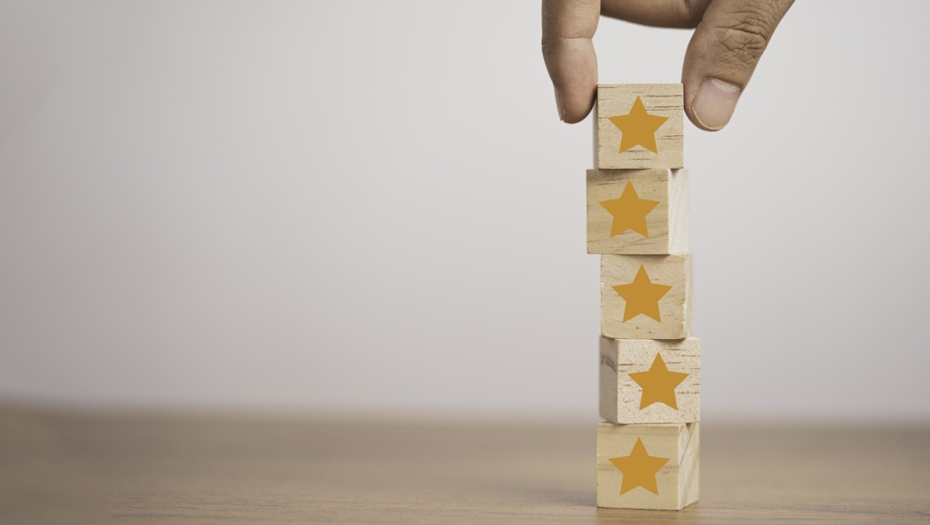 Hand putting yellow stars which print screen on wooden cube block for customer satisfaction concept.